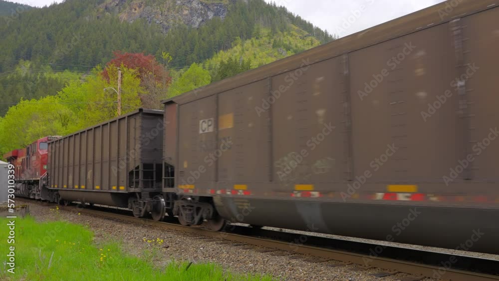 Establishing shot of freight train moving on the forest background in slow motion at summer day in Vancouver, Canada, North America. Day time on September 2021. Still camera. ProRes 422 HQ.
