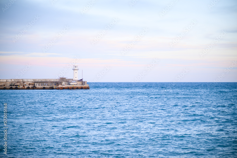 View of Lighthouse on pier with sea and sky in distance