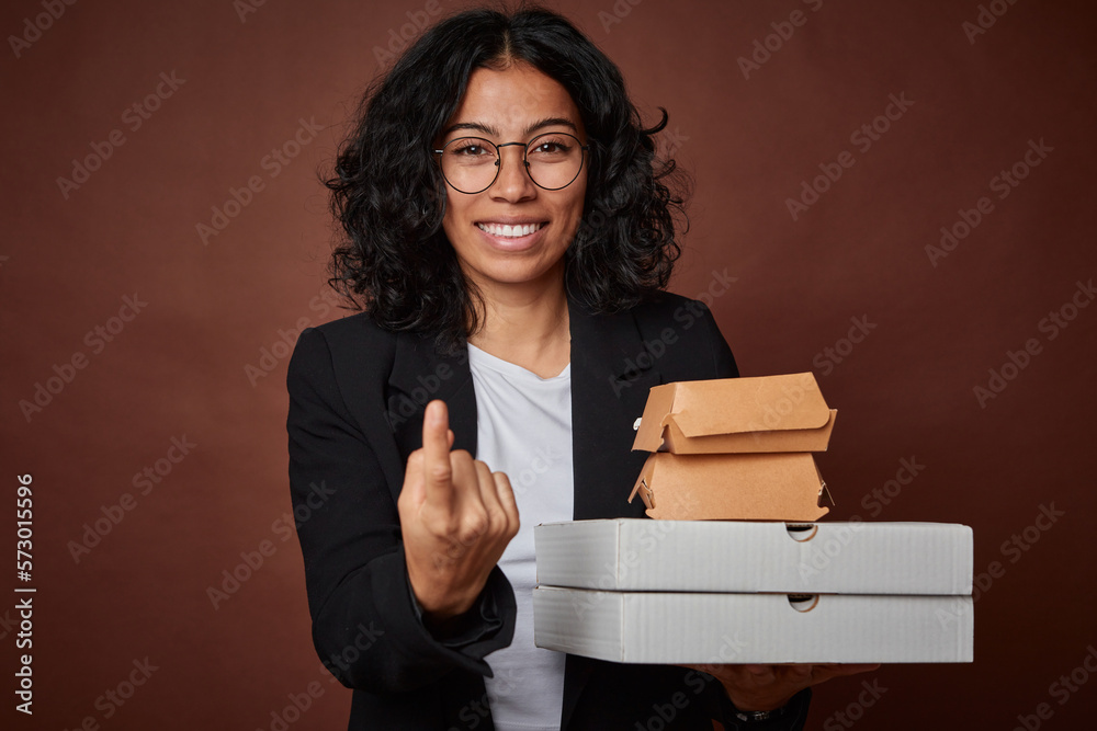 Naklejka premium Young business woman holding a fast food pack pointing with finger at you as if inviting come closer.