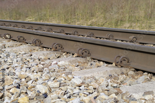 Tory kolejowe z bliska, stalowe szyny i betonowe podkłady kolejowe.
