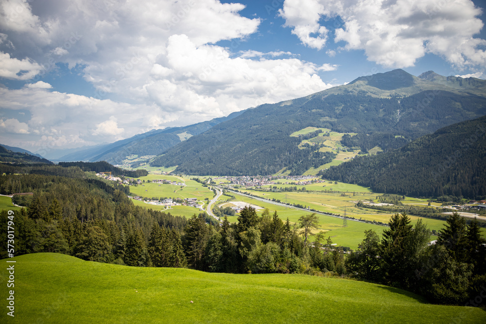 green alpine valley with forest and farmhouses
