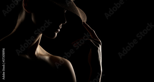 Sensual portrait silhouette of beautiful woman with a hat in backlight on a black studio background