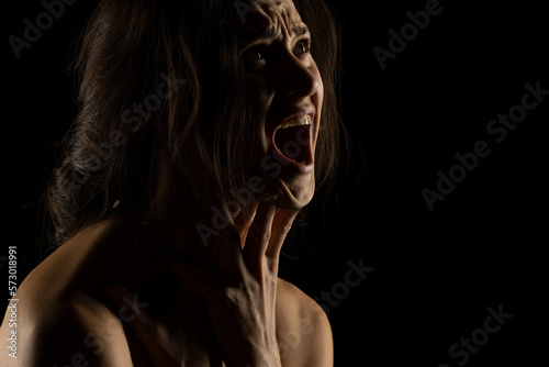 Silhouette of young unhappy screaming woman on black background © vladimirfloyd