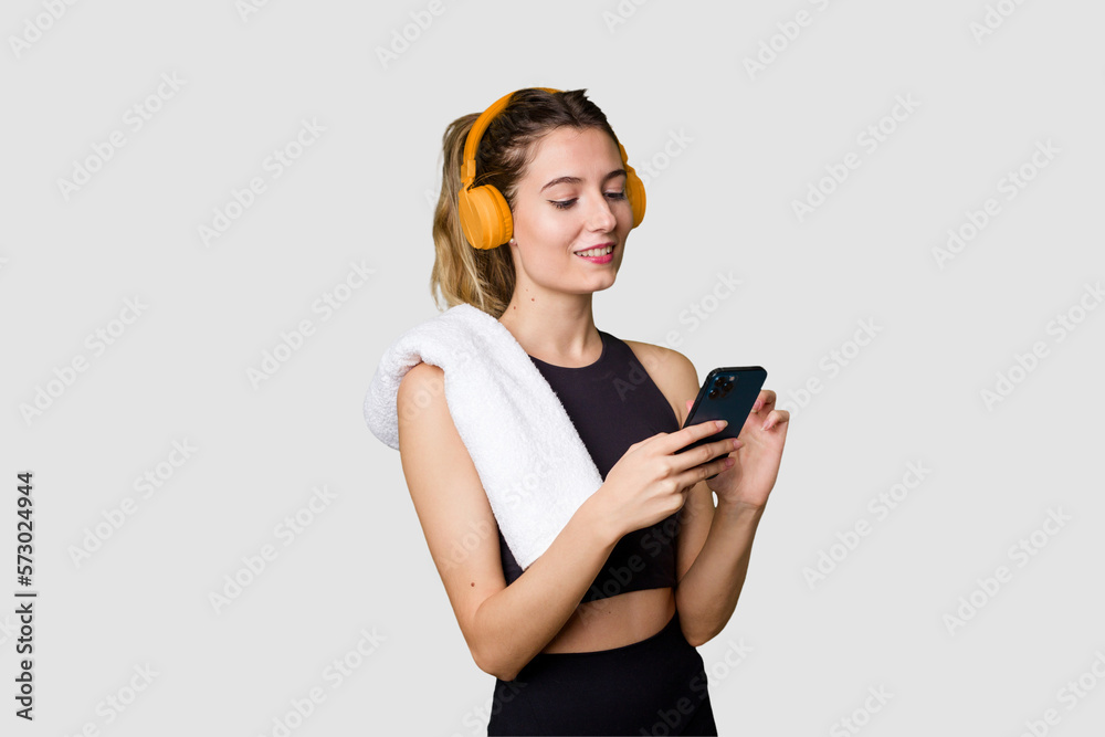Naklejka premium Young sportswoman listening to music, motivated and focused, holding phone