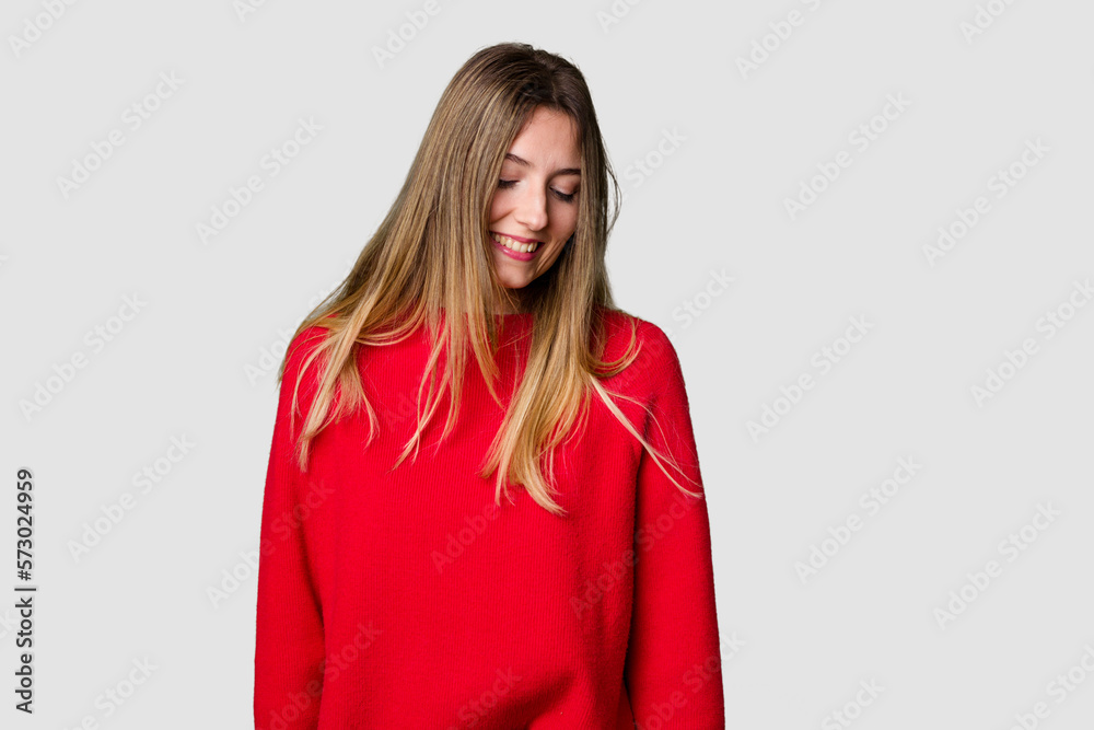 Young blonde posing for a portrait isolated, exuding natural beauty and radiance laughs and closes eyes, feels relaxed and happy. Young blonde posing for a portrait isolated, exuding natural beauty and radiance laughs and closes eyes, feels relaxed and happy.