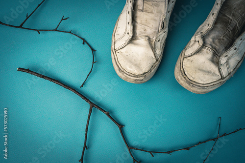 Фотография old battered women's sneakers without laces on a blue background.