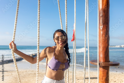 Young tourist with sexy and beautiful smile attentive to the ropes of the swing in the Mexican Mayan Riviera, enjoying while swinging and contemplating the spectacular views of a beautiful white beach