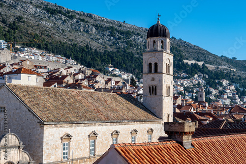 Franciscan Church and Monastery rising above Stradun street in amazing, fortified city of Dubrovnik, with rows of houses on the steep slopes in the background photo