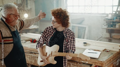 carpenter and his musician grandson are rejocing on a new guitar in the workshop photo