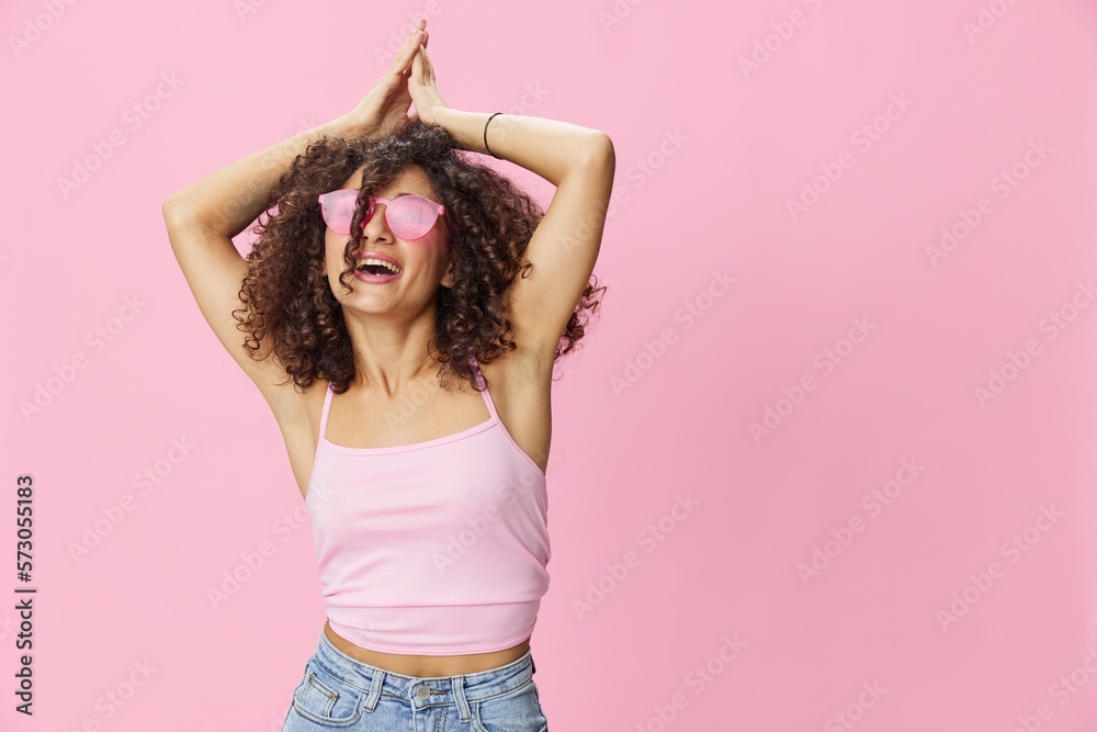 Happy woman afro curls hair dancing on a pink background in summer pink t-shirt jeans and glasses, summer vibe, copy space Happy woman afro curls hair dancing on a pink background in summer pink t-shirt jeans and glasses, summer vibe, copy space