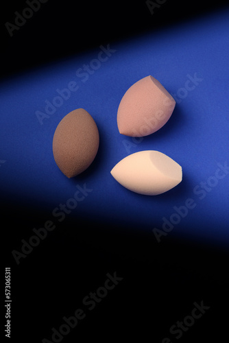 Cuadro en lienzo Three different cosmetic blenders on a blue background with a contrast shadow