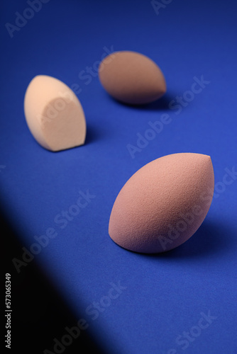 Cuadro en lienzo Three different cosmetic blenders on a blue background with a contrast shadow