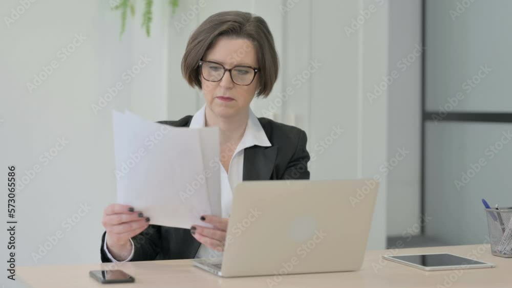 Old Businesswoman Working on Laptop and Documents