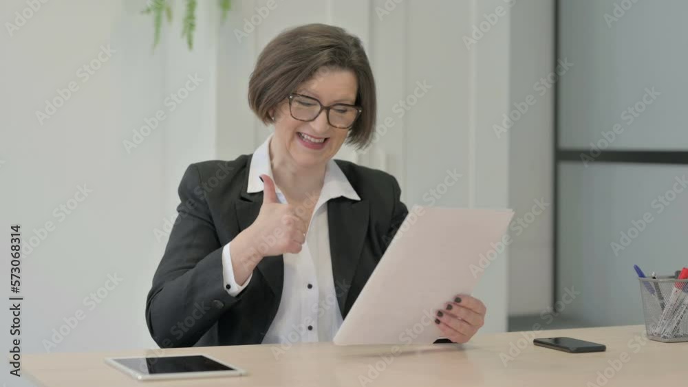 Old Businesswoman Celebrating Success while Reading Documents in Office Old Businesswoman Celebrating Success while Reading Documents in Office