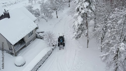 Blue tractor cleans up snow from the yard