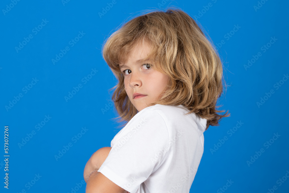 Portrait of angry child on blue studio isolated background. Upset kid upset kid boy with mad expression.