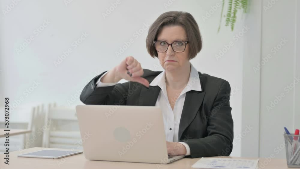 Thumbs Down by Old Businesswoman Working on Laptop Thumbs Down by Old Businesswoman Working on Laptop