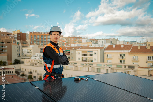 Engineer on the rooftop of a city building near solar panels looking at camera.