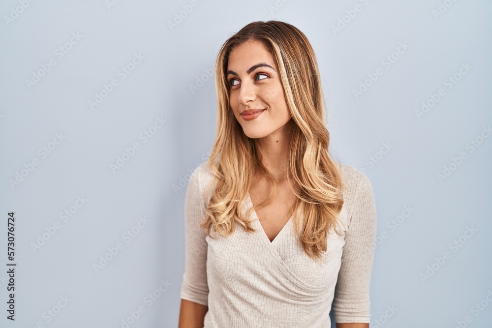 Young blonde woman standing over isolated background smiling looking to the side and staring away thinking. Young blonde woman standing over isolated background smiling looking to the side and staring away thinking.