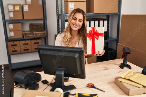 Young blonde woman ecommerce business worker having video call showing gift at office