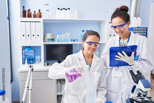Woman and girl wearing scientist uniform working at laboratory