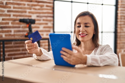 Middle age woman using touchpad and credit card standing at new home