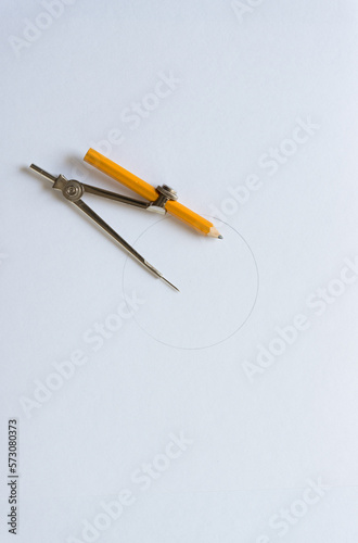 mathematical set instrument - compass with pencil on blank paper with circle