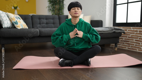 Young chinese woman training yoga exercise sitting on floor at home