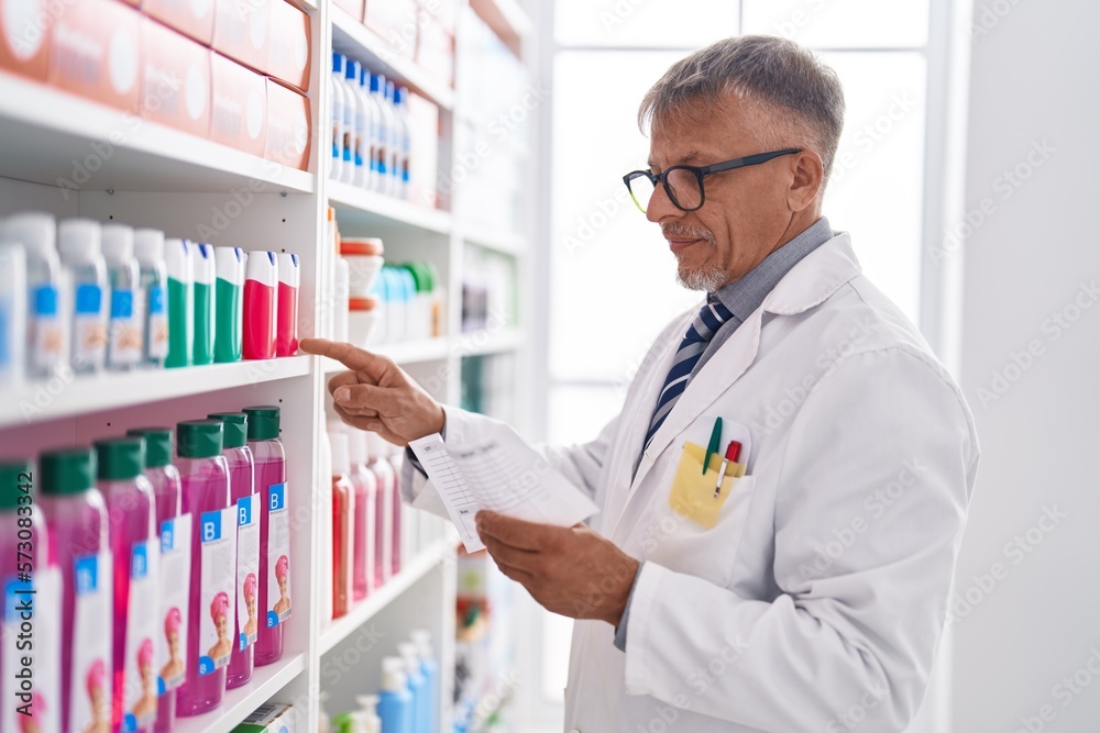 Middle age grey-haired man pharmacist reading prescription at laboratory