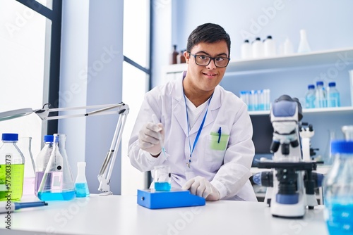 Down syndrome man wearing scientist uniform measuring liquid at laboratory