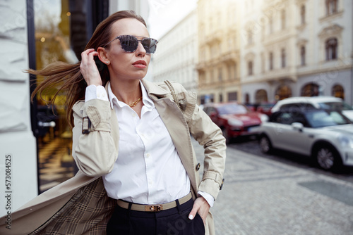 Stylish woman in coat standing on city street background and looking at side. High quality photo