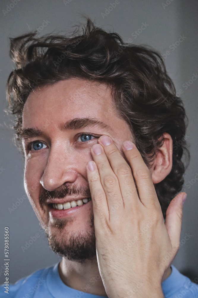 Handsome young man applying cream on his face Handsome young man applying cream on his face