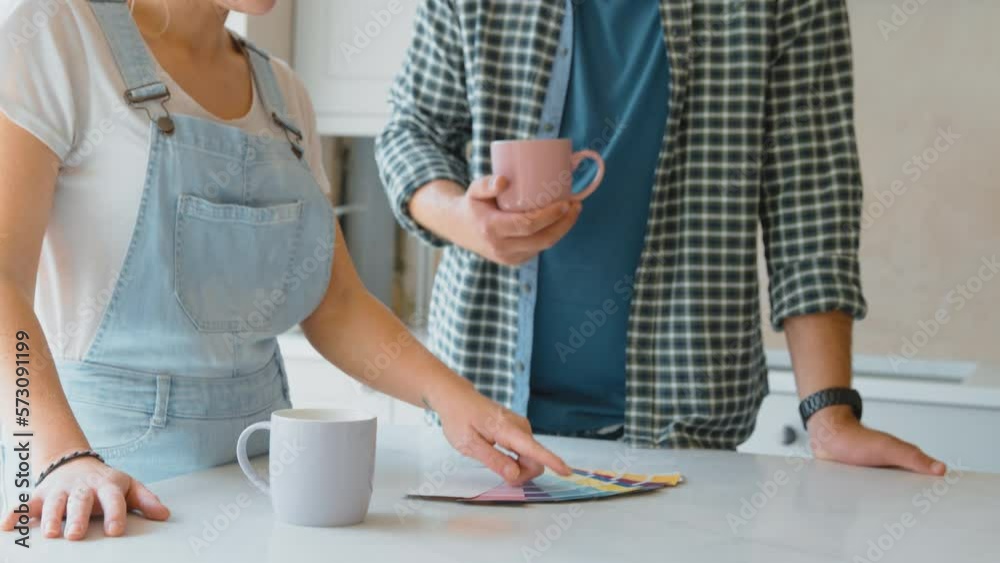 Camera tracks up to show couple renovating kitchen at home looking at paint colour swatches on coffee break - shot in slow motion Camera tracks up to show couple renovating kitchen at home looking at paint colour swatches on coffee break - shot in slow motion