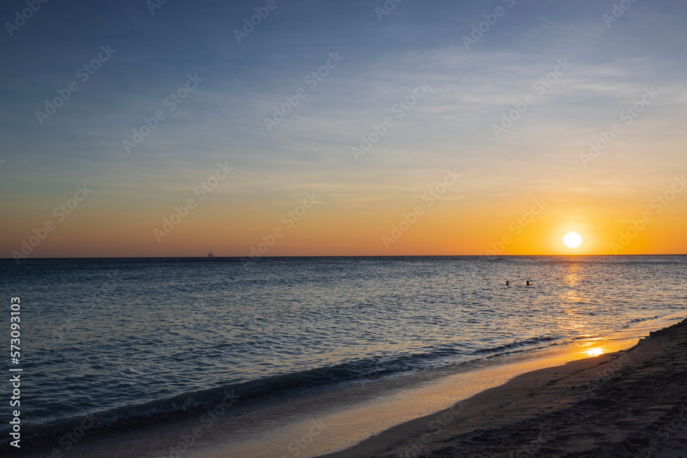 Gorgeous view of orange sunset on sandy beach of Eagle Beach in Atlantic Ocean on Aruba island.