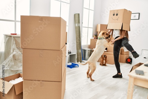 Photography Young hispanic woman wearing funny cardboard on head playing with dogs at new ho