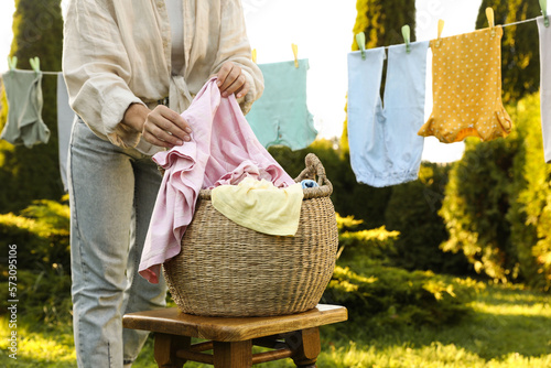 Canvastavla Woman hanging baby clothes with clothespins on washing line for drying in backya