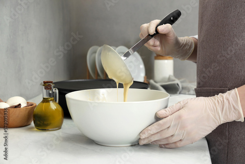 Woman cooking delicious crepe at white marble table in kitchen, closeup