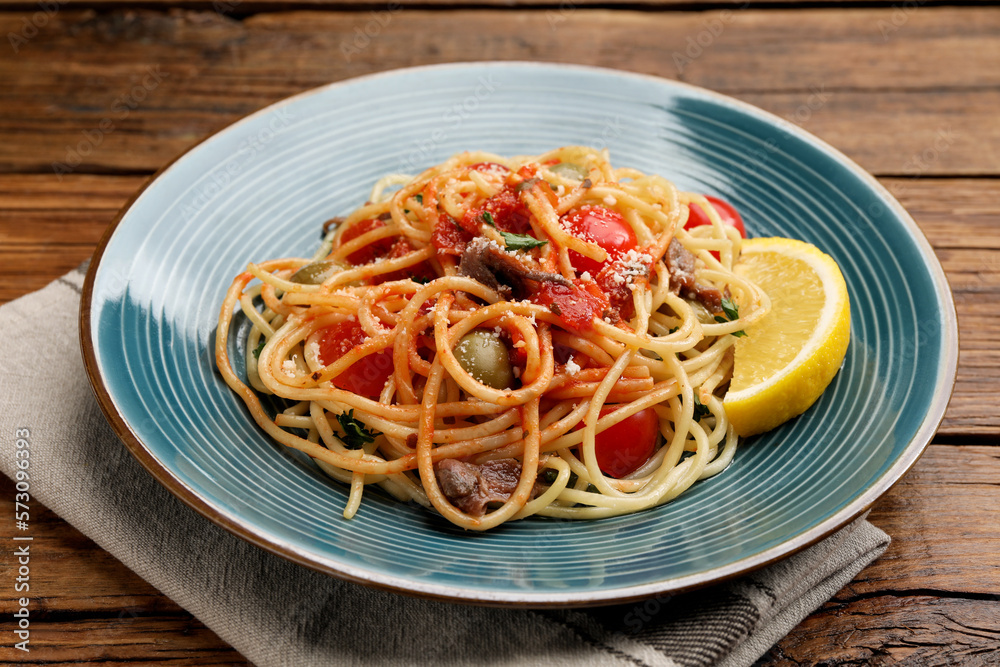 Delicious pasta with anchovies, tomatoes and parmesan cheese on wooden table, closeup