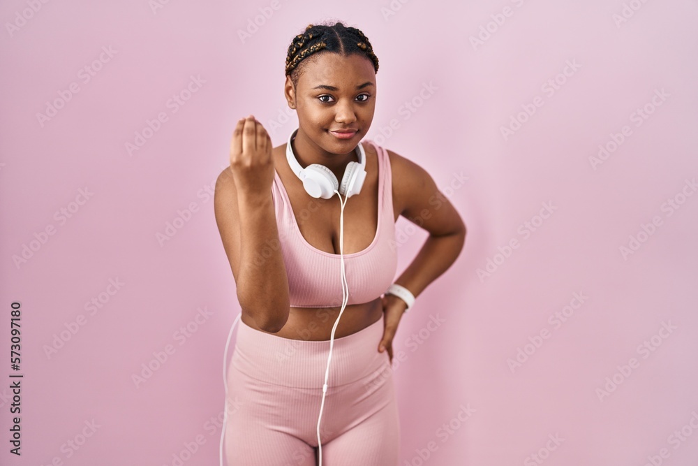 African american woman with braids wearing sportswear and headphones doing italian gesture with hand and fingers confident expression