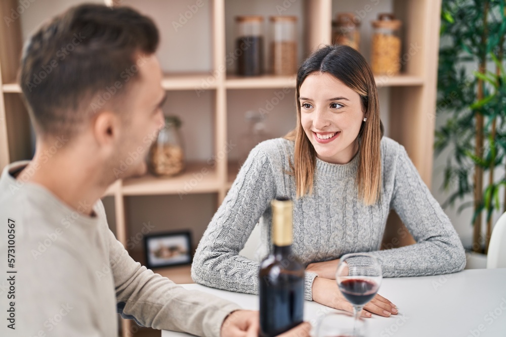 Man and woman couple drinking red wine sitting on table at home