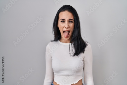 Hispanic woman standing over isolated background sticking tongue out happy with funny expression. emotion concept.