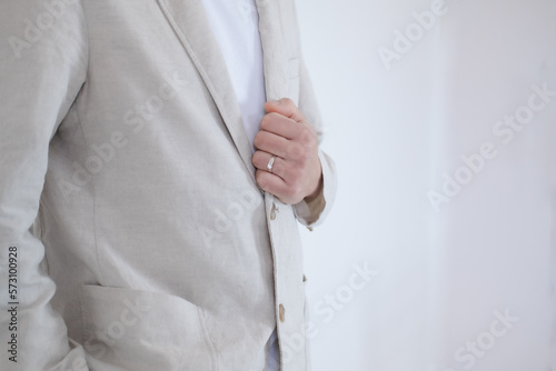 The groom wears a ring and holds his shirt on his wedding day.