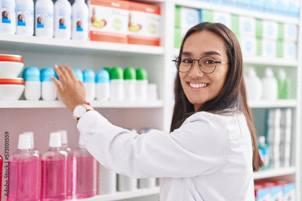 Young beautiful hispanic woman pharmacist smiling confident standing at pharmacy