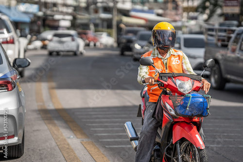 Thai courier on a motorcycle in city traffic