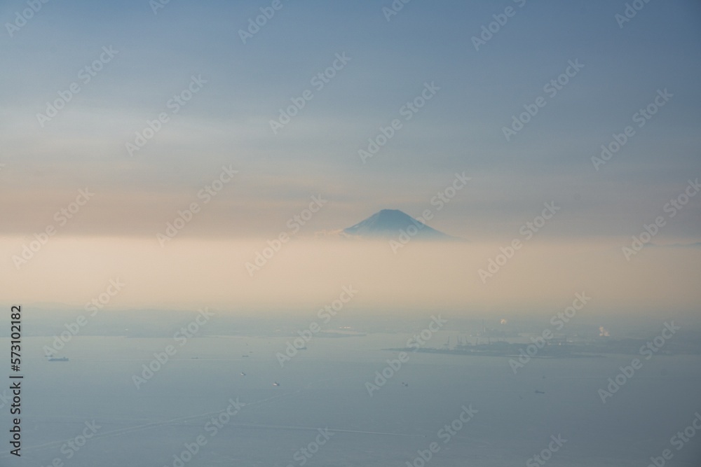 Tokyo, Japan - February 17, 2023: Aerial view of hazy Mt. Fuji over clouds
