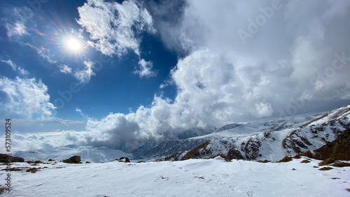 Beautiful blue sky and white clouds. Amazing view of the mountains covered with snow. Hiking in the mountains in winter.