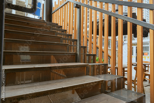 Close-up detail of wooden stairs with black steel mesh and golden fences. Stair case in modern building for decorating inspiration and background. Wooden stairway, design, furniture, building, modern.