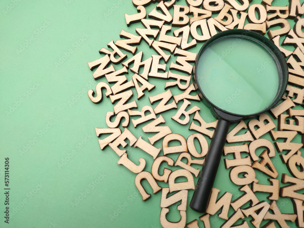 Wooden word and magnifying glass on a green background - obrazy, fototapety, plakaty 
