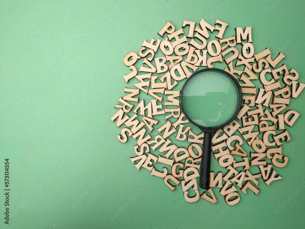 Wooden word and magnifying glass on a green background - obrazy, fototapety, plakaty 