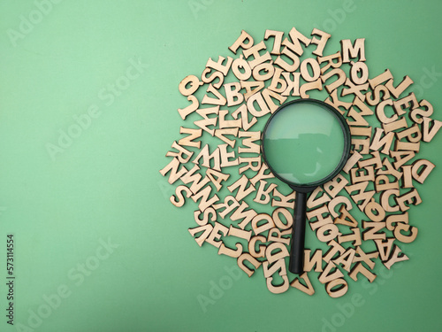 Wooden word and magnifying glass on a green background photo